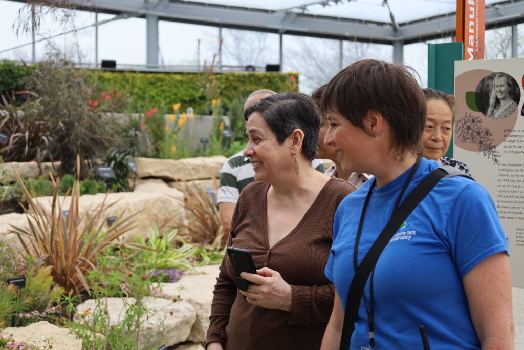 Two women smiling and walking together through a biodome at The Leaf