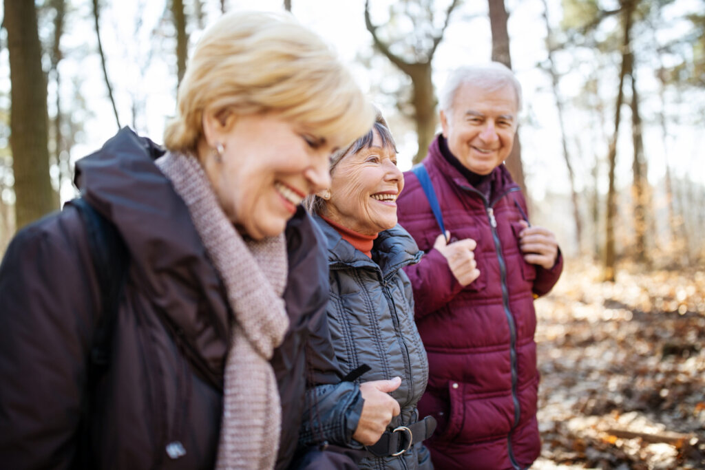 Senior man and women walking together through forest trail on a cold autumn day.