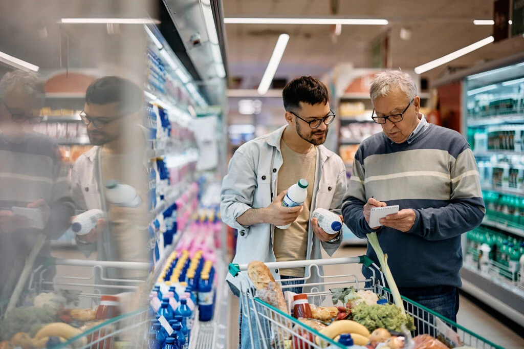 Young man and his senior father going through shopping list while buying groceries in the supermarket
