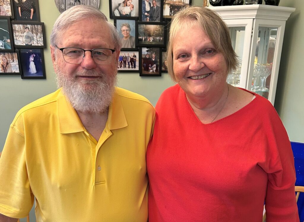 Bob McIntyre, and his wife Bev, are smiling, standing side-by-side in their home.