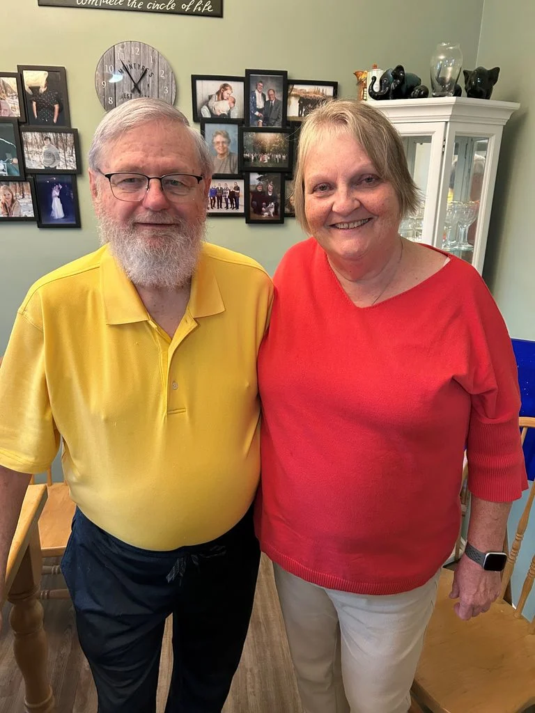 Bob McIntyre, and his wife Bev, are smiling, standing side-by-side in their home.