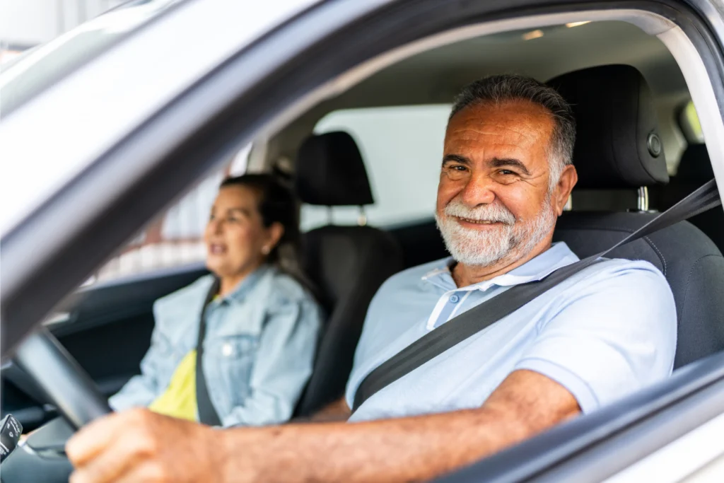 Man smiling in front seat of a car