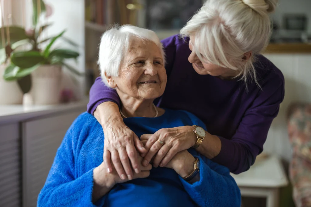 Senior woman being hugged by another senior woman