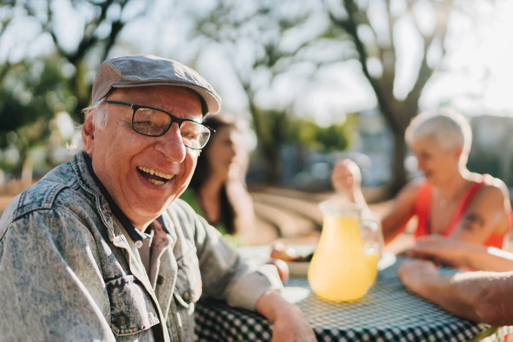 Senior man smiling with lemonade outside
